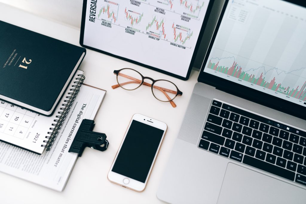 Mit Aktien gegen die Inflation 8 Kalender, Brille, Smartphone und Laptop auf weisem Tisch