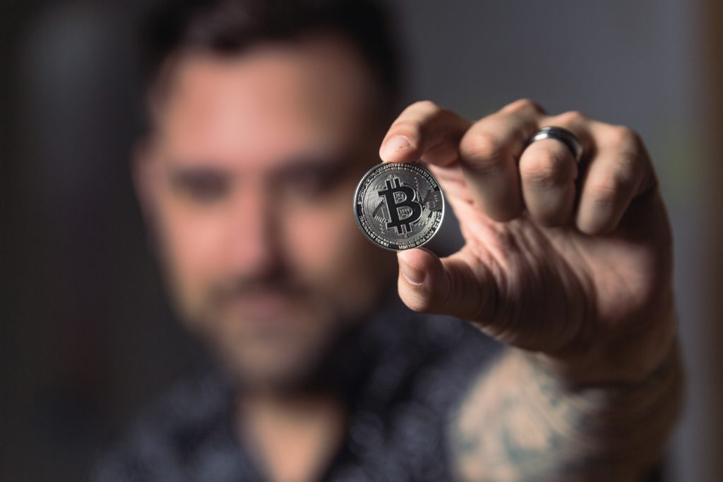 Mit Aktien gegen die Inflation 11 Mann hält silberne Bitcoin Münze in die Kamera
